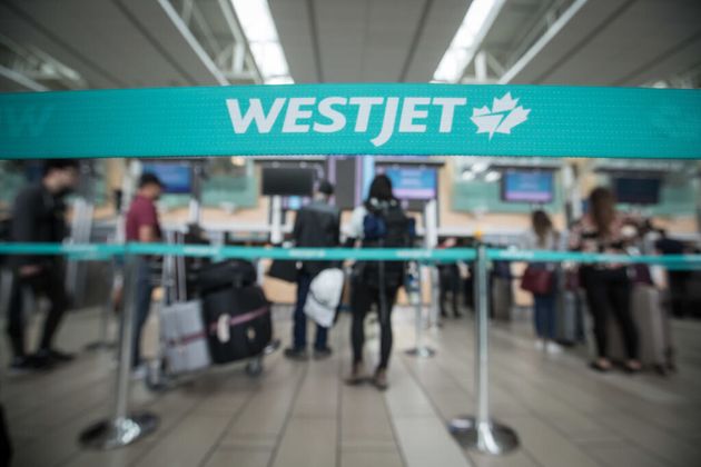 Travellers stand in line at Vancouver International Airport in May 2019. WestJet was previously offering customers flight credit or no-fee rebooking for flights to and from Europe.