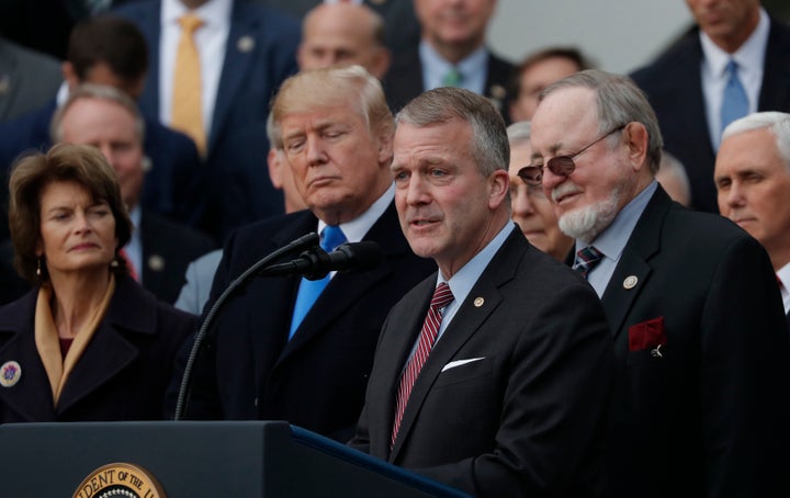 Sen. Sullivan, foreground, speaks at a ceremony celebrating Donald Trump's tax cuts. His fortunes could depend on whether Alaskans distinguish him from the president.