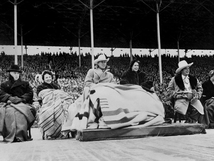 Princess Elizabeth and the Duke of Edinburgh wearing a blanket (a wedding present from Canada) watching the the Calgary Stampede during their 1951 visit. 