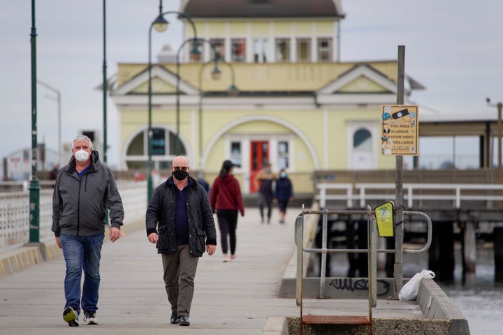 Walkers wear protective face masks at St Kilda pier in Melbourne after it became the first city in Australia to enforce mask-wearing in public.