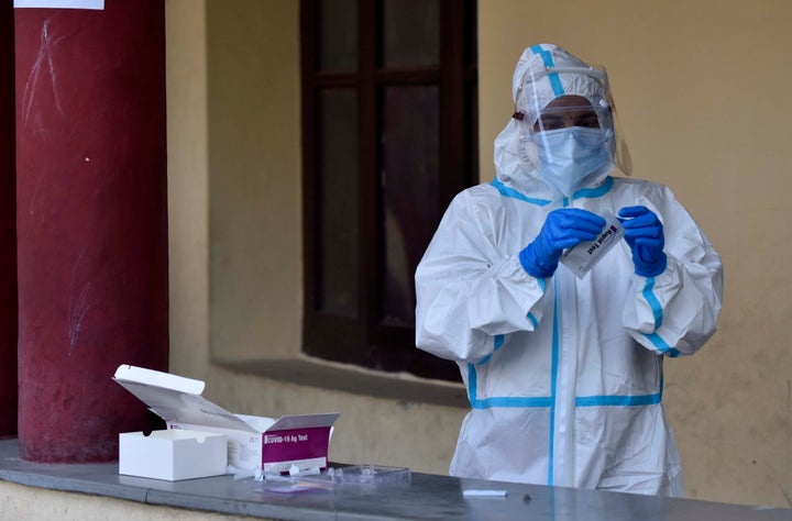 A health worker works with a rapid antigen based Covid-19 test kit at Drya Ganj on July 27, 2020 in New Delhi