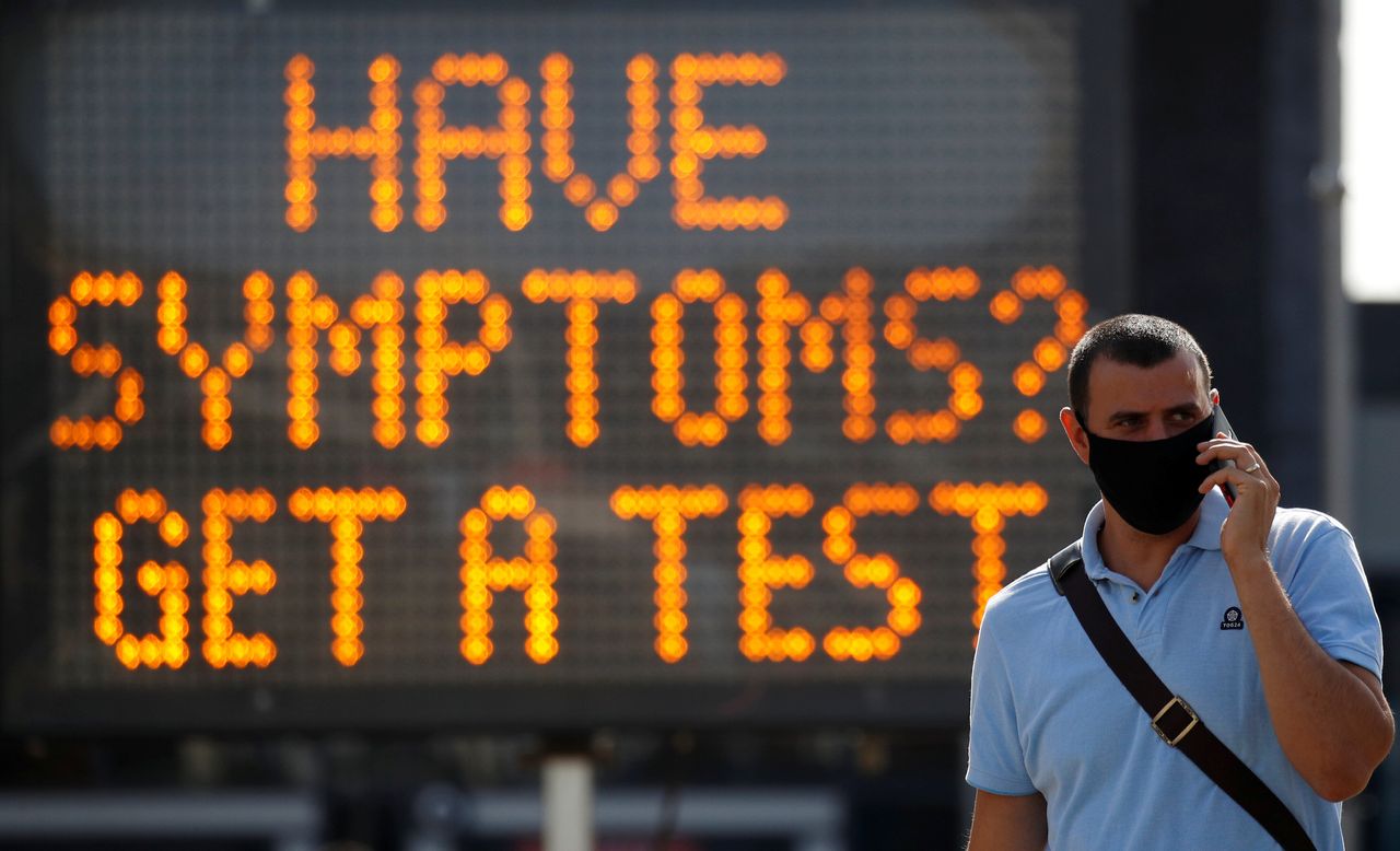 A man walk past an information board following the outbreak of coronavirus in Bolton.