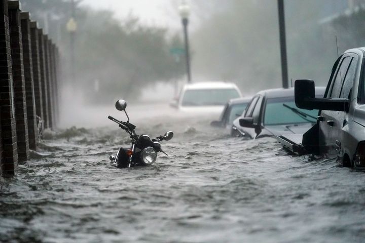 Cars and a motorcycle are underwater as water floods a street, Wednesday in Pensacola, Fla.