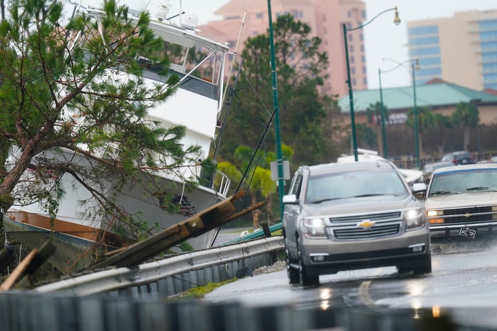 Vehicles maneuver on a flooded road Wednesday near a washed-up boat after Hurricane Sally moved through the area in Orange Beach, Ala.