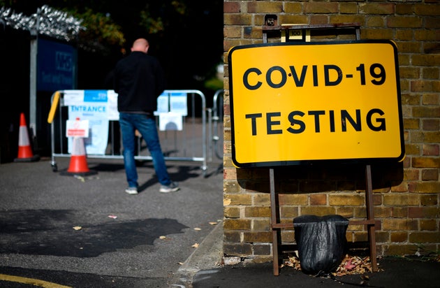 A man wearing a face covering due to the COVID-19 pandemic, queues to attend a coronavirus walk-in testing centre in East Ham in east London