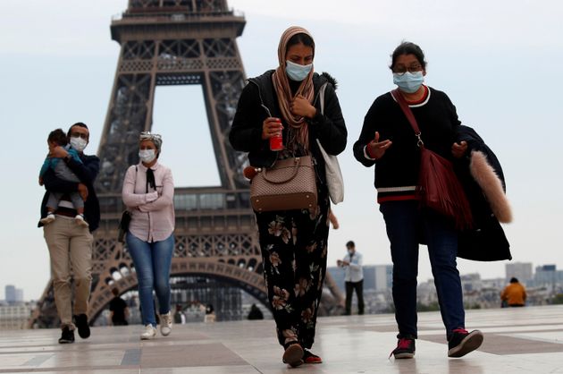 People with face masks walk through the Trocadero square, near the Eiffel Tower, as France began a gradual end ...