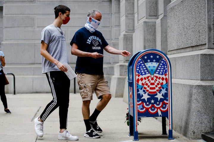 Benjamin Graff (center) and son Jacob Graff, 19, drop off their mail-in ballots for the Pennsylvania primary election in Philadelphia on June 2, 2020.