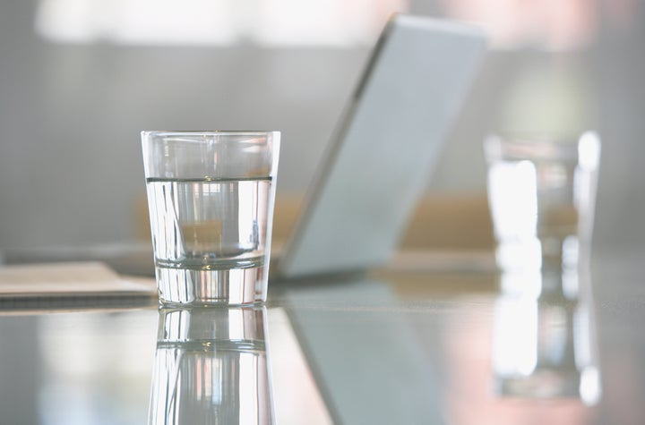 Close-up of glass with water on desk with laptop