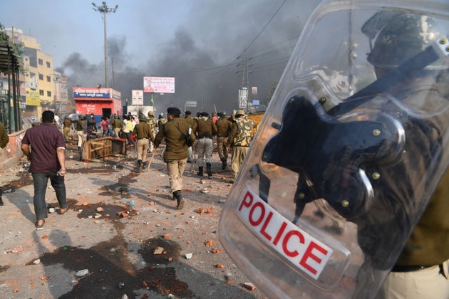 Police walk along a road following clashes at Bhajanpura area of New Delhi on February 24,