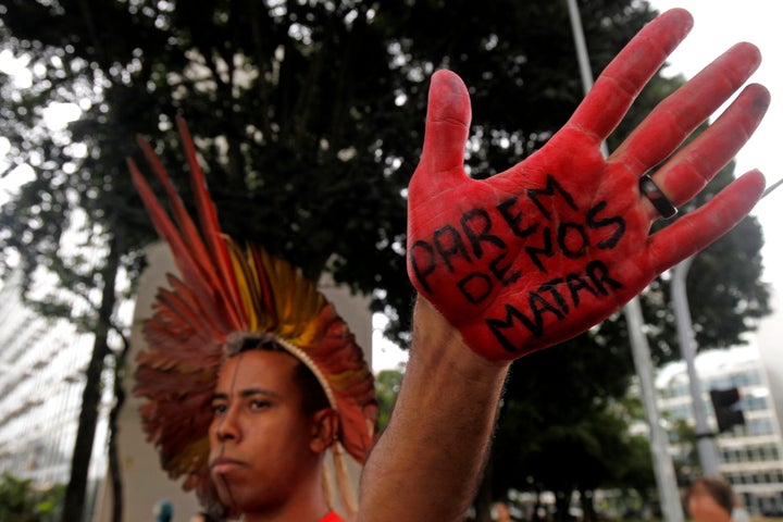 A man from the Xakriabá people shows his hand covered with the Portuguese phrase: "Stop killing us" during a protest against a government proposal for legislation that would allow mining on indigenous lands, outside Congress in Brasilia, Brazil, in February 2020.