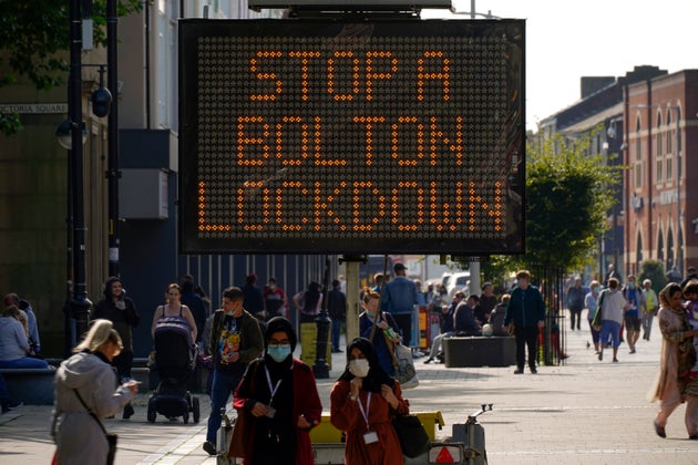 BOLTON, ENGLAND - SEPTEMBER 17: People walk past an electronic sign displaying health advice about COVID-19  on September 17, 2020 in Bolton, England. Fears about rising infection rates among younger people across the Uk has forced the government into tighter lockdown restrictions, particularly in the North of England.  (Photo by Christopher Furlong/Getty Images)