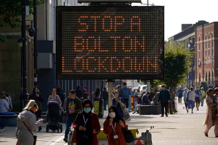 BOLTON, ENGLAND - SEPTEMBER 17: People walk past an electronic sign displaying health advice about COVID-19 on September 17, 2020 in Bolton, England. Fears about rising infection rates among younger people across the Uk has forced the government into tighter lockdown restrictions, particularly in the North of England. (Photo by Christopher Furlong/Getty Images)