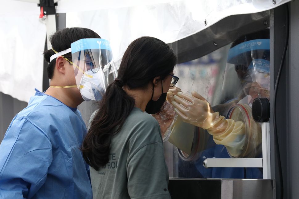 A medical worker takes samples from a woman during the COVID-19 testing at a temporary test facility on Aug. 26 in Seoul, South Korea. Anyone who has symptoms in Korea, or who may have contacted a person confirmed to have the virus, regardless of symptoms, can get tested.