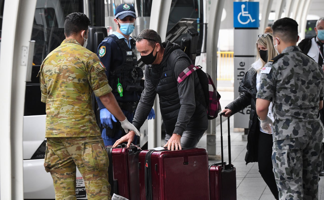 Passengers hand over their luggage to enter a hotel quarantine at Sydney International Airport on Aug. 8 in Australia. Authorities impose a mandatory hotel quarantine for 14 days for all arriving passengers.