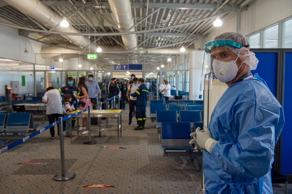 Medical staff wait to test passengers who arrive into Athens, where authorities perform random tests.