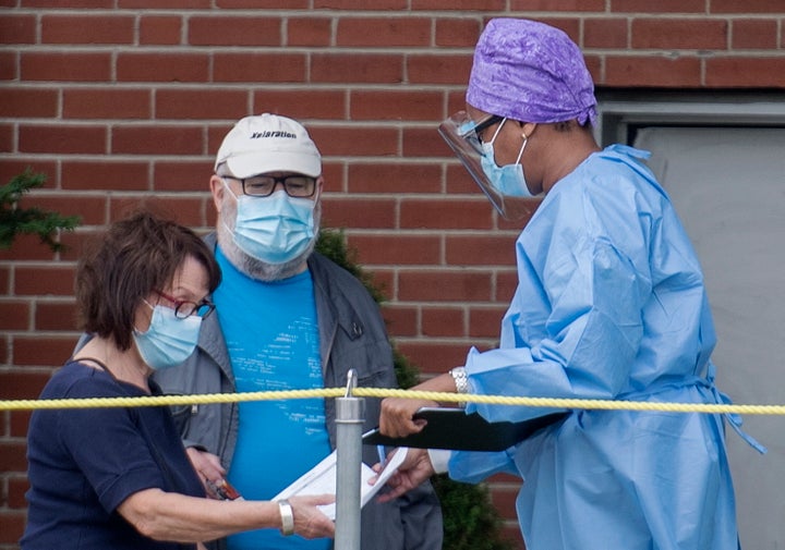 A health-care worker talks with people outside a COVID-19 testing clinic in Montreal on Sept. 7, 2020.