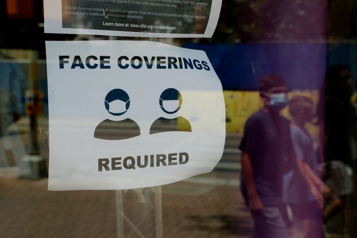 A visitor wearing a mask to protect against the spread of COVID-19 passes a sign requiring masks in San Antonio, Texas.