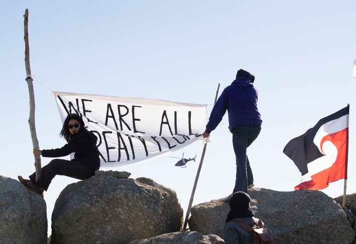 Sipekne'katik First Nation community members waved a flag that said, "We are all treaty people," while a coast guard helicopter hovered in the background in Saulnierville, N.S., on Sept. 20, 2020.