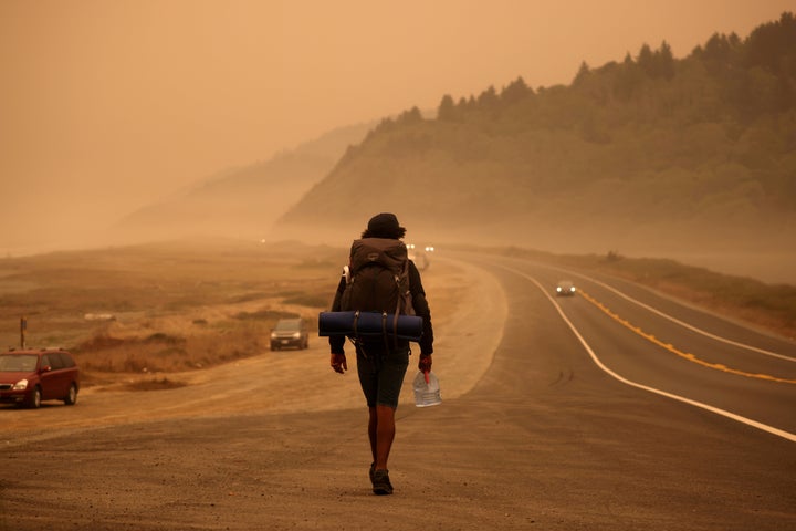 A man walks along the Redwood Highway by the Pacific Ocean coast as smoke from wildfires covers an area near Orick, Californi