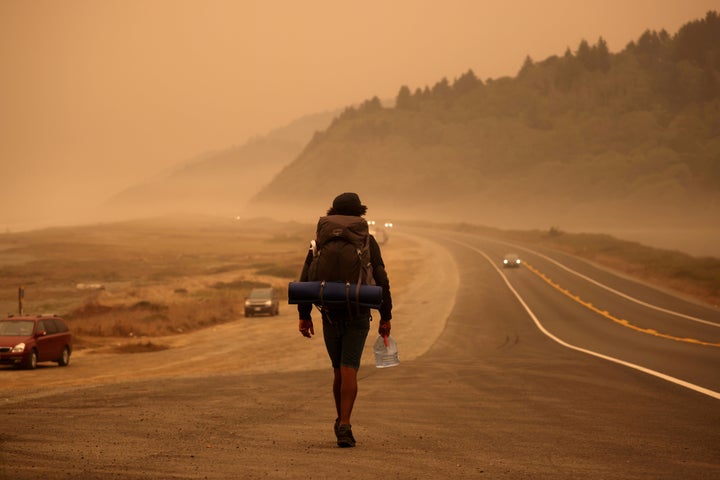 A man walks along the Redwood Highway by the Pacific Ocean coast as smoke from wildfires covers an area near Orick, California, on Sept. 9.