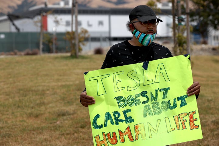 Tesla worker Carlos Gabriel holds a sign at a demonstration outside the Tesla plant in Fremont, California, on June 15, prote