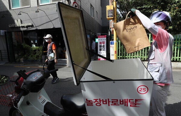 23일 오후 서울 마포구 포은로 망원시장 놀장 픽업센터에서 고형락 배달매니저(오른쪽)가 각 상점으로 주문된 물건을 가지고 와 가정으로 배달하기 위해 오토바이에 싣고 있다.