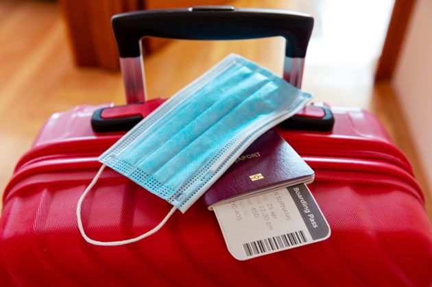 Face protection mask and travel documents over trolley bag.