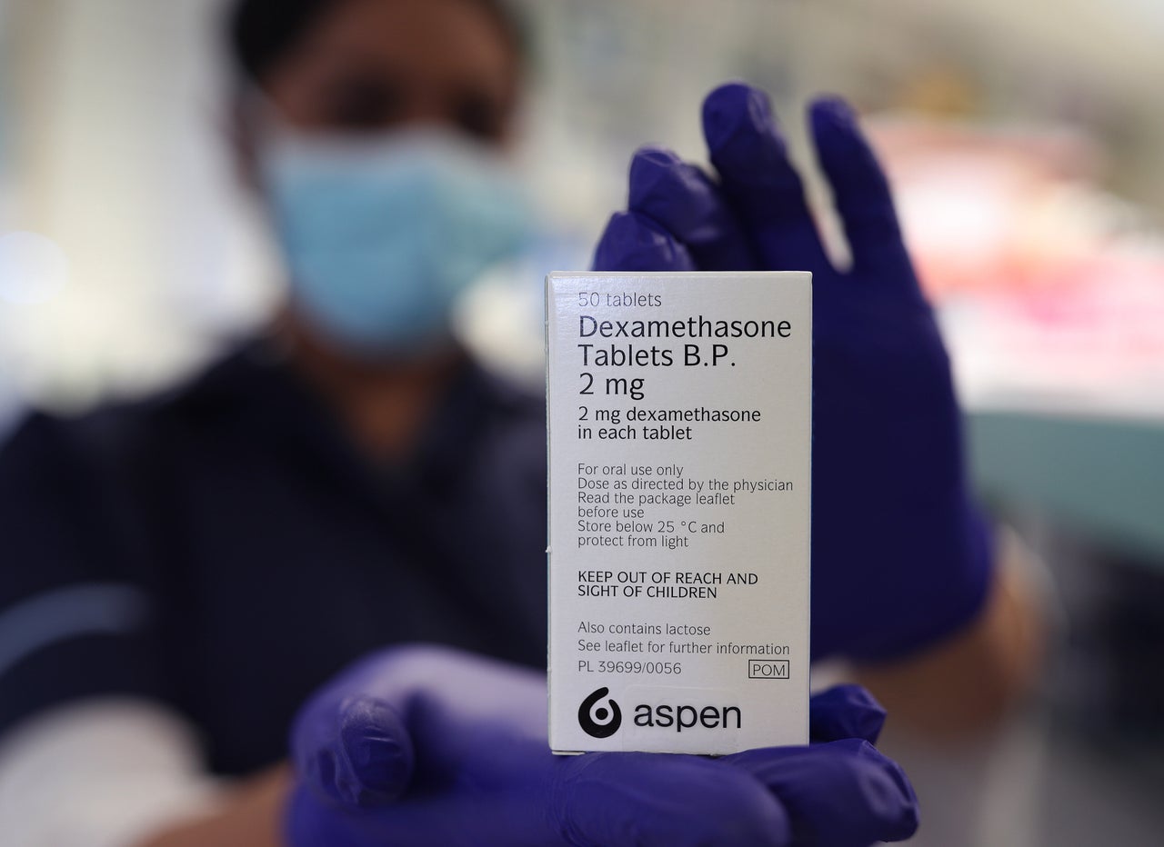 A member of staff at a pharmacy in London holds a packet of anti-inflammatory drug dexamethasone