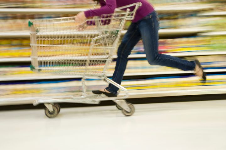 Woman riding grocery cart in supermarket aisle