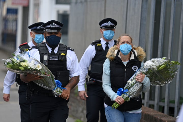 Police officers wearing protective face masks bring floral tributes to the Croydon Custody Centre where the incident took place