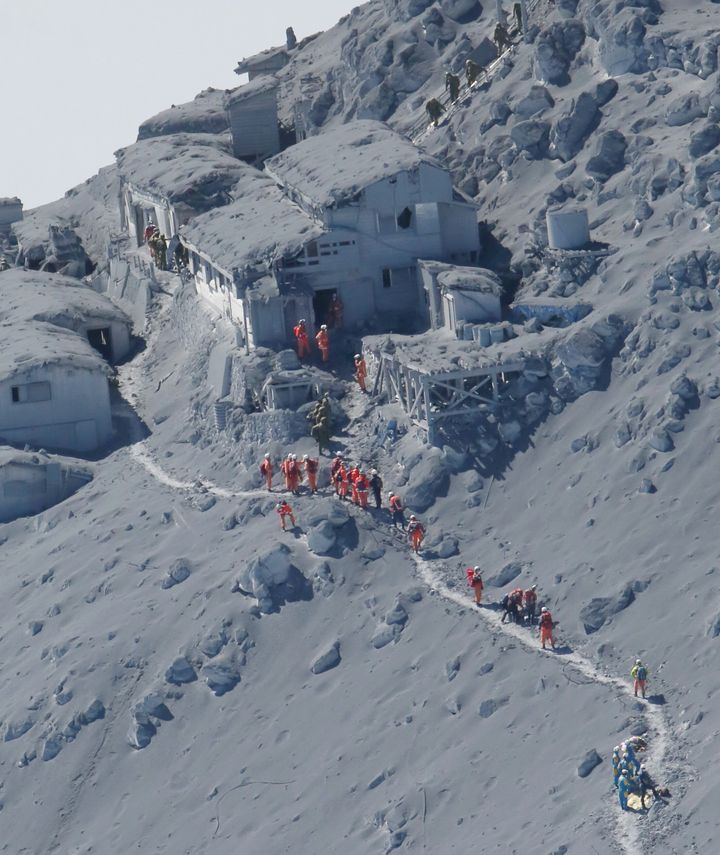 噴火翌日、御嶽頂上山荘に到着した救助隊。灰が積もり、山荘の屋根には噴石による穴が開いている＝2014年9月28日、御嶽山上空［時事通信社ヘリより］ 
