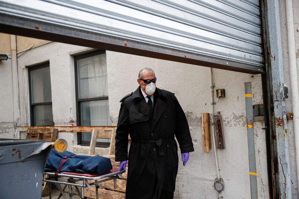 Ένας νεκροθάφτης ενώ συλλέγει μια σορό από γεροκομείο στο Μπρούκλιν της Νέας Υόρκης, 3 Απριλίου 2020. «Πήραμε ένα όρκο να προστατεύουμε τους νεκρούς», λέει. «Είμαστε οι τελευταίοι που επεμβαίνουμε. Η δουλειά μας είναι όσο σημαντική είναι εκείνων των πρώτων βοηθειών». (AP Photo/John Minchillo)