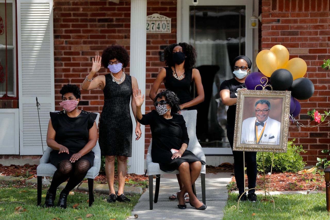 Νέα Ορλεάνη, 22 Απριλίου 2020. Η οικογένεια του Λάρυ Χάμοντ χαιρετά τους φίλους και συγγενείς που περνάνε με τα αυτοκίνητα έξω από το σπίτι τους, αφου δεν μπορούσαν να είναι στην κηδεία λόγω του περιορισμού των 20 ατόμων στις κηδείες. (AP Photo/Gerald Herbert)