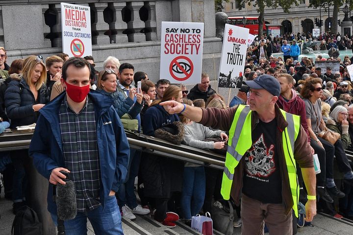 A protester (R) gestures to a member of the media (L) as he complains about the wearing of a mask, in Trafalgar Square.