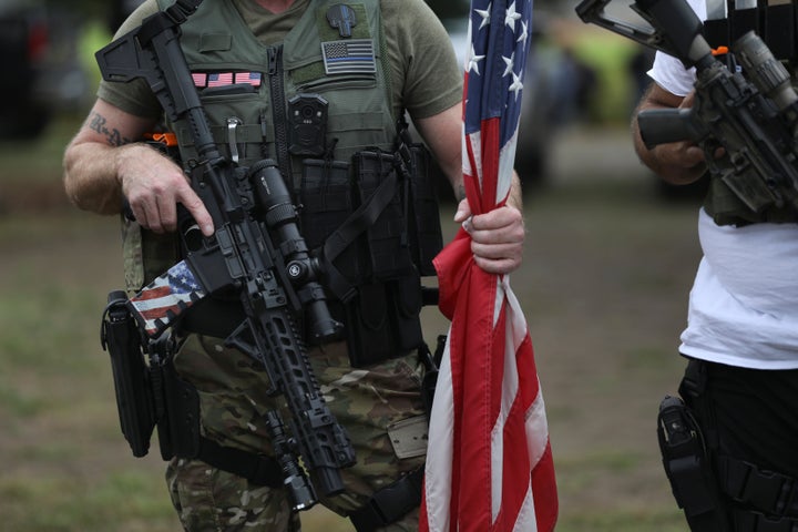 A person holds a weapon and a flag as members of the Proud Boys and other right-wing demonstrators gather in Portland. Thousa