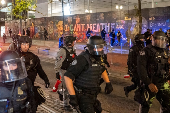 Portland police disperse a crowd of protesters past a mural of George Floyd and Breonna Taylor in Portland on Saturday. Orego