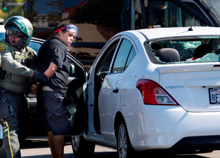 An unidentified woman is seen being taken into custody after witnesses said she drove her car into a crowd of protesters in Yorba Linda, leaving two people injured.