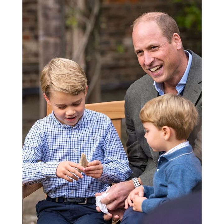 Prince George holds a shark tooth, as his father Prince William and brother Prince Louis look on.