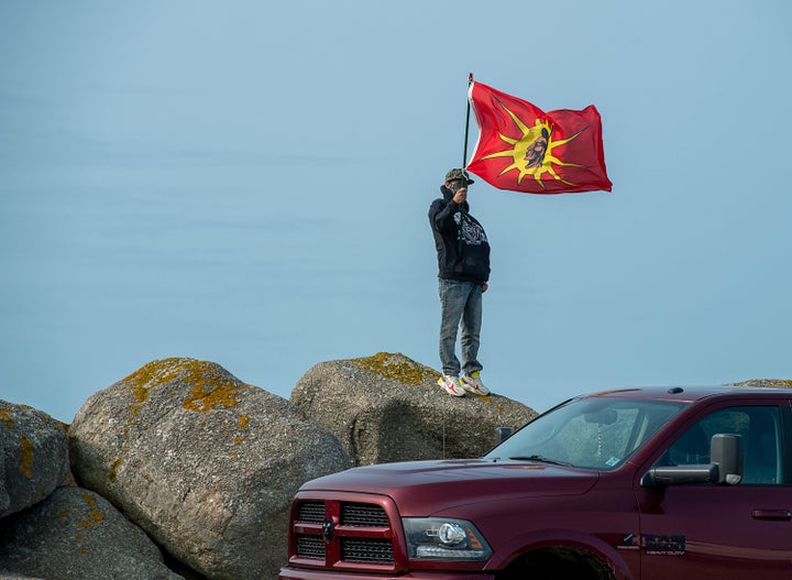 A man flies a warrior flag as members of the Sipekne'katik First Nation gathered on the wharf in Saulnierville, N.S. on Sept. 17, 2020.