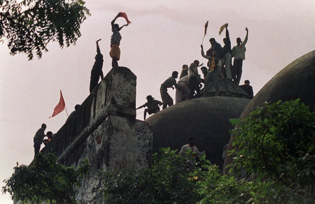 File photo taken on December 6, 1992 shows kar sevaks shouting and waving banners as they stand on the...