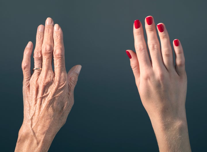 Studio photograph of elderly woman's hand beside a younger woman's hand.