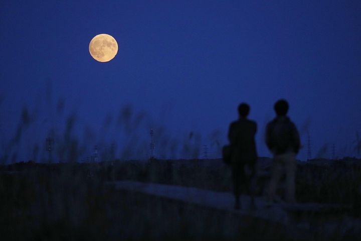夜空に浮かび上がった中秋の名月を見る人々＝2019年9月13日、北海道石狩市 