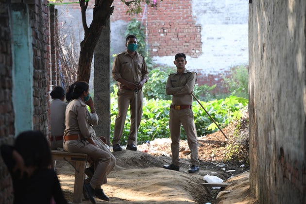 Uttar Pradesh Police personnel stand outside the family house of a 19-year-old woman, who was allegedly...