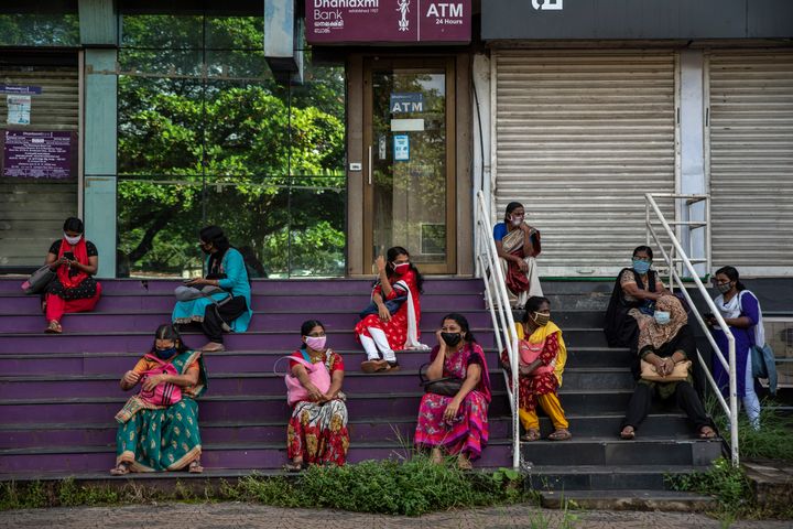 Women who arrived for work await information after the Cochin Special Economic Zone that houses several industrial units was closed as part of COVID-19 containment measures in Kochi, Kerala, Oct.1, 2020.