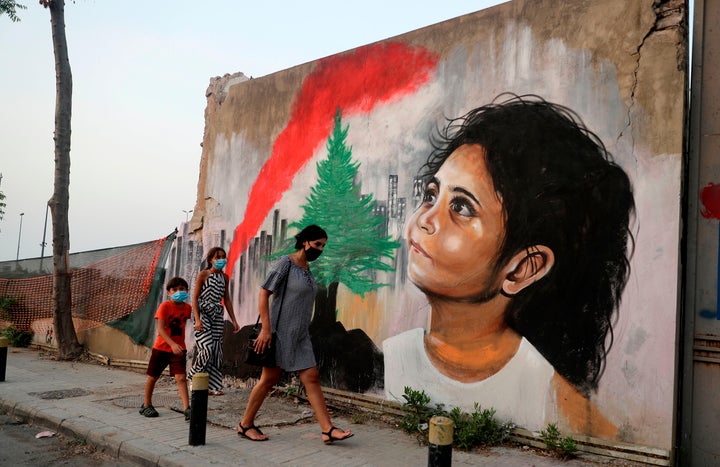 Mask-clad pedestrians walk past a mural painting on September 4, 2020, depicting a young Lebanese girl who suffered a face injury in the August 4 massive blast at the nearby seaport, one month after the disaster that left scores of people dead or injured and ravaged swaths of the capital Beirut. (Photo by JOSEPH EID / AFP) (Photo by JOSEPH EID/AFP via Getty Images)