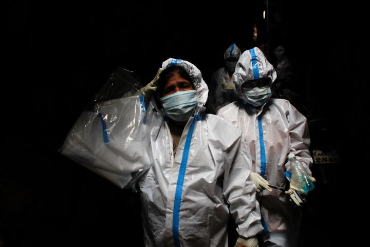 A health worker in personal protective equipment reacts as she and the rest of the team walk through an alley during a check up campaign for the coronavirus disease (COVID-19) at a slum area in Mumbai, India, August 3, 2020. 