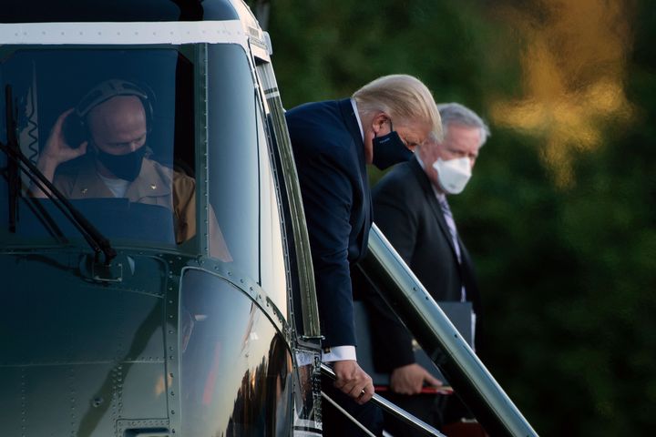 Donald Trump steps off Marine One while arriving at Walter Reed National Military Medical Center as White House Chief of Staff Mark Meadows looks on.