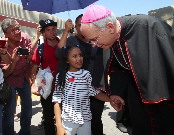 El Paso's Roman Catholic Bishop Mark Seitz escorts Celsia Palma, 9, of Honduras, and her family across a point of entry on the U.S.-Mexico border so the family could be processed into the U.S. on June 27, 2019, in Juarez, Mexico.