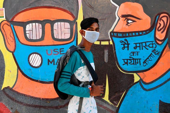 A man walks past a mural representing frontline warriors of the Covid-19 coronavirus, painted on the wall of a dumping ground in New Delhi on September 29, 2020. 