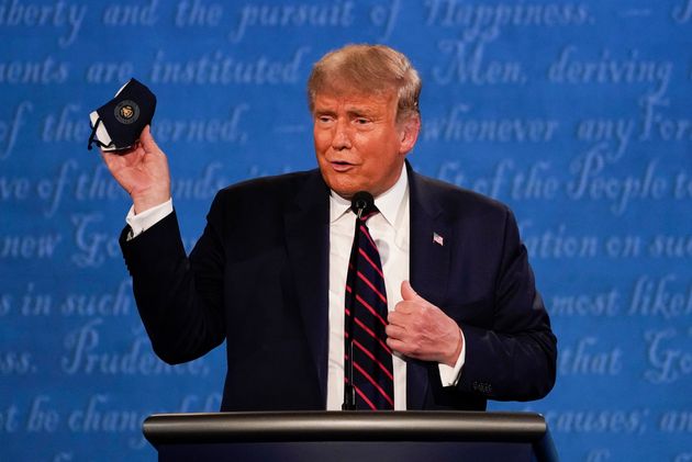 Trump holds up his face mask during the first presidential debate on Tuesday.